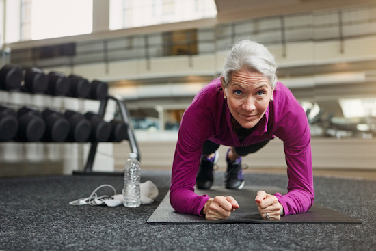 older woman doing a plank at the gym